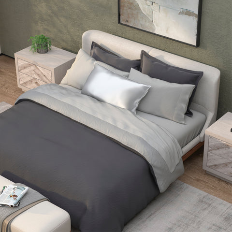 A modern, neatly-made bed with plush gray and white bedding in a tranquil bedroom setting, complete with matching nightstands, serene wall art, and PureCare Soft Touch Bamboo pillow shams.