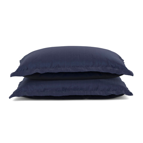 Two stacked navy blue pillows with a ruffled edge design and PureCare Cooling Bamboo pillow shams isolated on a white background, suggesting a comfortable and stylish addition to home bedding.