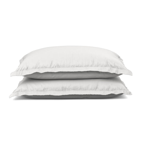 Two plush white pillows stacked neatly against a pure white background, suggesting comfort and simplicity for a peaceful sleeping environment, are complemented by PureCare Cooling Bamboo pillow shams.
