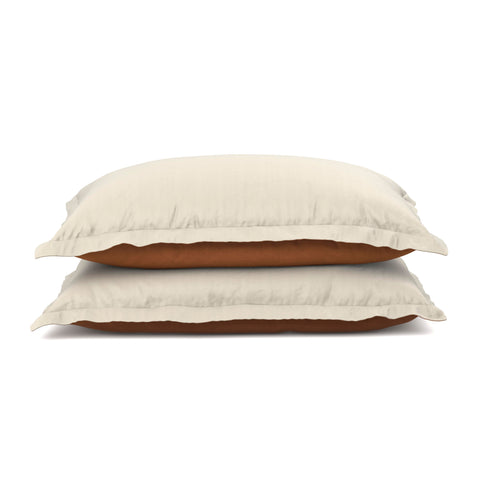 Two plush pillows with PureCare Cooling Bamboo pillow shams and brown piping are stacked on a plain white background, exuding simplicity and comfort.
