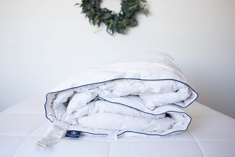 A Pacific Coast Feather SuperLoft™ Down Comforter on a white bed with a wreath on it.