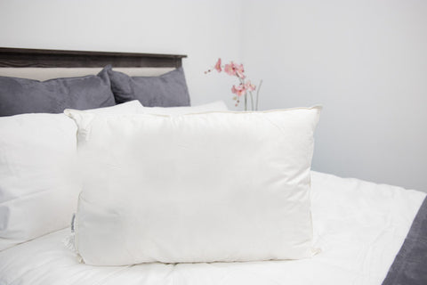 A white pillow on the bed made of Pillowtex 50% White Duck Feather/50% Microfiber Pillow.