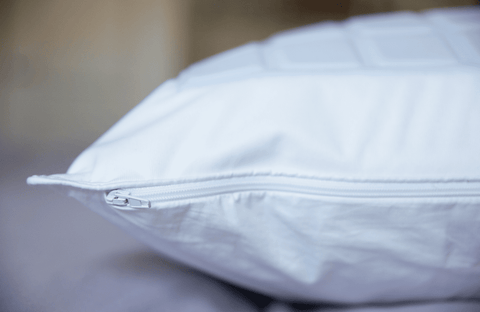 A Pillowtex Cooling Gel Pillow Protector made of 100% cotton on a bed.