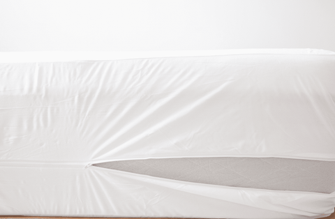 A bed with a Pillowtex Deluxe Mattress Protector in white on top of it.