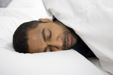 A man sleeping peacefully on a bed with a Pillowtex Down Alternative Blanket and Pillowtex pillows.