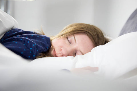 A woman sleeping on a Pillowtex Green Tag Super Soft Pillow in a bed.