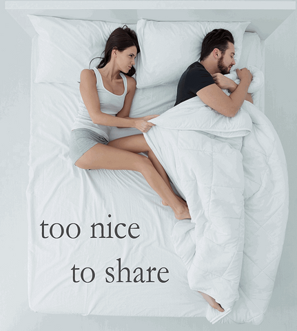 Two people lying in bed with a Pillowtex High End Down Comforter, too nice to share.