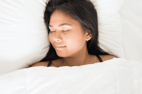 A woman sleeping in bed with her eyes closed on a Pillowtex High End White Goose Down Pillow | Soft Support.