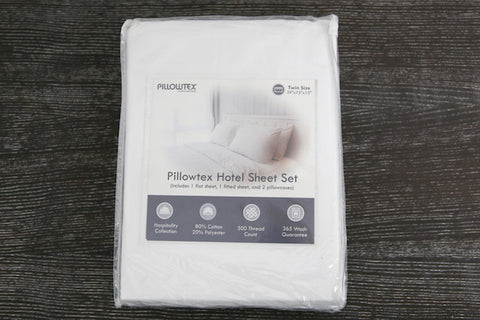 A white Pillowtex Hotel Sheet Set made of 300 thread count cotton & polyester blend fabric set on a wooden table.