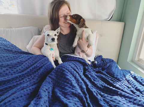 A woman cuddles her dogs in bed under a Pillowtex Minky Dot Reversible Duvet Cover for Weighted Blanket.