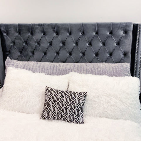 A bed with a tufted headboard and Pillowtex Body Pillow Cover in Colorful Plush Faux Fur pillows.