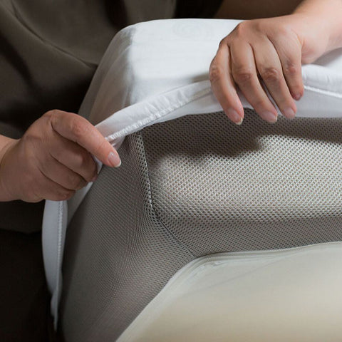 A person is covering a chair with a Protect-A-Bed Premium Mattress Protector.