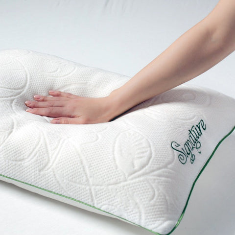 The woman's hand is gently touching a Protect-A-Bed Naturals Pillow on the bed, which features Cooling Memory Foam Fill for added comfort.