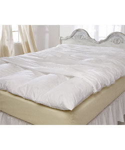A bed with a white comforter made of Rocky Mountain Feather and Down® Featherbed Protector by Rocky Mountain Feather and Down.
