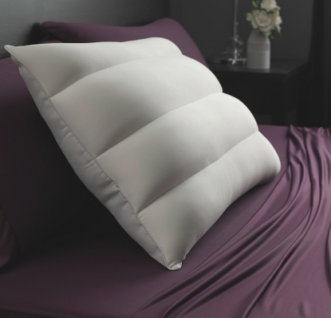 Two SHEEX 4 Channel Performance Density Pillows designed for side sleepers rest on a smooth, purple satin bedsheet, offering a contrast of comfort and luxury in a serene bedroom setting.