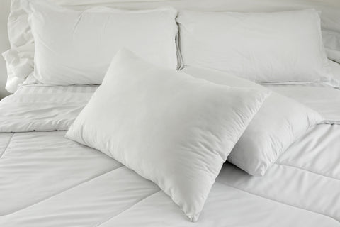 A white bed with Creative Bedding Fossfill Pillows filled with antibacterial FossGuard™ protection.