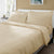 A neatly made bed with Delilah Home’s Final Sale: Organic Hemp Bed Sheet Collection in light beige, two large matching pillows, and a duvet. Tan walls, a white headboard, and natural light by the window complete the serene space.