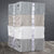 Four neatly folded stacks of Delilah Home’s Final Sale: Organic Hemp Bed Sheet Collection in soft grey, beige, and white are tied with white ribbon featuring a round logo, resting on a wooden surface against a dark background.
