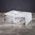 A neatly folded Delilah Home Final Sale: Organic Hemp Bed Sheet Collection in light gray, tied with a white ribbon bearing a circular logo, rests on wood with a dark gray background—luxuriously temperature regulating and ready for gifting or display.