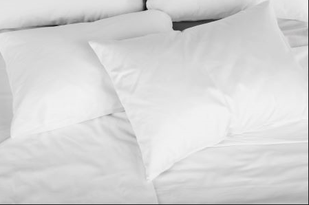A monochromatic image of a neatly made bed with crisp white sheets and hypoallergenic, Westin® Heavenly Firm Support Polyester Bed Pillows by Hollander inviting a peaceful and comfortable rest.