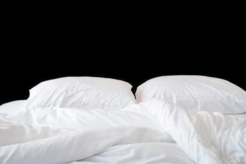 A bed with white sheets and pillows featuring a Pillow Factory 100% White Duck Down Duvet Insert on a black background.