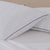 Two La-Z-Boy Down Alternative Pillows with dotted patterns and dark piping rest on a crisp white bed, complemented by a light beige headboard for a clean and inviting look.