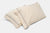 Two cream-colored American Blossom Linens pillowcases, made from 100% USA cotton, feature a smooth texture and minimalist black piping near the edge for an elegant touch. They are overlapped on a white background.