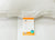 A close-up of the HD Supply Best Western® Dreammaker Gusseted Pillow (Medium-Firm Support) shows a bright orange and white label with product details and a blue logo, partially visible beneath the pillow on crisp white bedding.