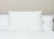 The Pillow Factory Housekeeper's Choice Heavenly Spiral Pillow—featured at many Borgata Hotel Casino & Spa®—sits upright on a bed with a white comforter, flanked by two more matching hotel pillows for a minimal, tidy look.