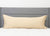 A long body pillow with a Pillowtex Body Pillow Cover, featuring antimicrobial copper-infused bamboo, is set against a tall gray headboard on a neat white bed, creating a clean and minimal bedroom look.