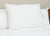 The Pillow Factory Housekeeper's Choice Heavenly Spiral Pillow, featured at many Borgata Hotel Casino & Spa<sup>®</sup>, sits upright on a neatly made bed with white linens, complemented by a wooden headboard and clean beige wall.
