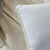 A close-up of the La-Z-Boy Hybrid Bliss Memory Foam | Richloft Fiber Foam Core Pillow, featuring a white, smooth, moisture-wicking cover and a small tagged corner with a blue dot, resting on soft beige sheets with gentle folds.