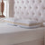 Two La-Z-Boy Hybrid Bliss Memory Foam | Richloft Fiber Foam Core Pillows with beige edges are stacked on a textured white mattress, complemented by a tufted headboard and wooden lamp for a stylish, moisture-wicking sleep setup.