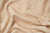 A close-up of the American Blossom Linens Herringbone Weave Blanket, made from organic cotton in the USA, shows its soft beige and white textured surface with gentle folds—heirloom quality comfort at its coziest.