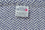 A close-up of the American Blossom Linens label sewn onto the Herringbone Weave Blanket, made from 100% USA organic cotton and showcasing heirloom quality craftsmanship by your friends and neighbors.