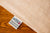 A close-up of American Blossom Linens' Colored Cotton Bed Pillowcases shows natural heirloom cotton fabric with a sewn-in tag that reads “100% USA ORGANIC COTTON,” listing care instructions in English and Spanish. Made in the USA.