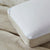 A close-up of the La-Z-Boy Hybrid Bliss Memory Foam Pillow shows its soft, smooth, moisture-wicking cover on a beige fabric surface. The pillow has a subtle quilted edge and a small white control panel with blue buttons in the top left corner.