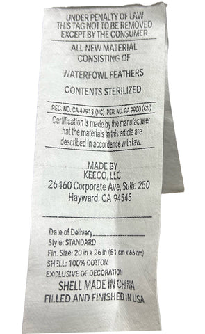 This image shows a close-up of a care label on a Pacific Coast Feather Pillow. The label includes text regarding material composition, care instructions, size, and regulatory compliance, with specific details like.