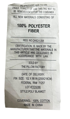 A crumpled Pillow Factory clothing tag displaying information such as content being 100% polyester, certification number, and details about the manufacturer, sold by, date of delivery, size, lot number, style number