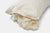 The American Blossom Linens American Made Wool Filled Pillow features organic cotton fabric and adjustable firmness, with a cream cover and soft, curly wool filling visible through a partially open zipper against a white background.