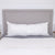 The Pillowtex Premium Polyester Body Pillow by Pillowtex, featuring medium support and a large rectangular design, rests on a neatly made bed with gray and white bedding, complementing light nightstands and a white shiplap wall.