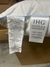 Close-up image of two tags on a white pillow. The left tag contains detailed manufacturing and material information in black text, including the company name Carpenter Co., and cautionary statements about tag removal. The right tag, labeled "Holiday Inn® Touch of Down Feather & Down Pillow," specifies the pillow type as "King - Soft Support" in English, Spanish, and French.