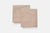 Two neatly folded, light beige pillowcases from American Blossom Linens rest on a plain light gray background. Their natural heirloom cotton fabric and clean edges reflect the simple elegance of American-made bedding.