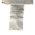 A close-up of a crumpled white care label attached to a JS Fiber Gold Choice Polyester Pillow Featured in Some Embassy Suites | Extra Loft, displaying black text that includes legal warnings, a certification number, and "made in u.s.a.