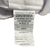 A close-up of a white care label attached to a JS Fiber Dacron II Quallofil | Extra Plump pillow, displaying text that includes material composition (100% polyester fiber), certification details, and.