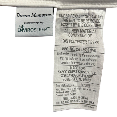 Close-up of a Manchester Mills clothing label with "Envirosleep Dream Memories by exclusively" printed at the top. Information includes material content (100% polyester), manufacturer details, and care instructions. The label notes that the Envirosleep Dream Memories Memorelle Fiber Fill Pillow item