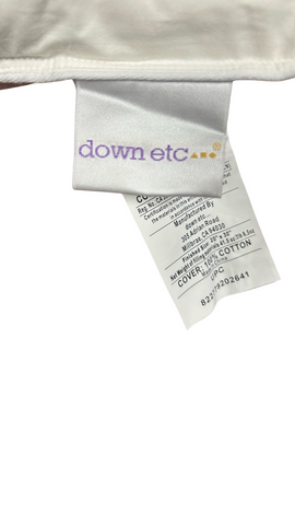 A close-up view of a Down Etc. Rhapsody Wrap Duck Feather & Down Pillow label showing product information, including material composition—specifically mentioning rds white duck down—and a visible upc barcode on an isolated background.