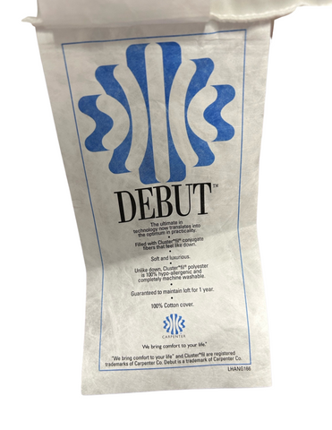 A folded Carpenter® Co. Debut Supreme Cluster Fiber Pillow cover with blue printed text, highlighting its ultra-soft and luxurious qualities, hypoallergenic 100% cotton composition, and a one-year guarantee.