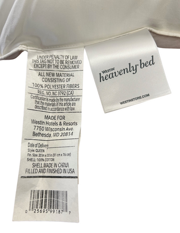 Close-up of a Westin® Heavenly Firm Support Polyester Bed Pillow made by Hollander indicating it's made of 100% polyester fibers, certified as class 1 by the California Department of Consumer Affairs, with information on size.