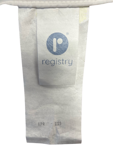 An upright disposable paper cup with the logo "Registry Down Alternative Polyester Pillow | Soft" on the label, marked with an expiration date of April 2023.